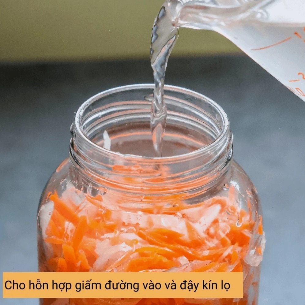 Đổ nước giấm đường vào lọ thủy tinh đựng rau củ