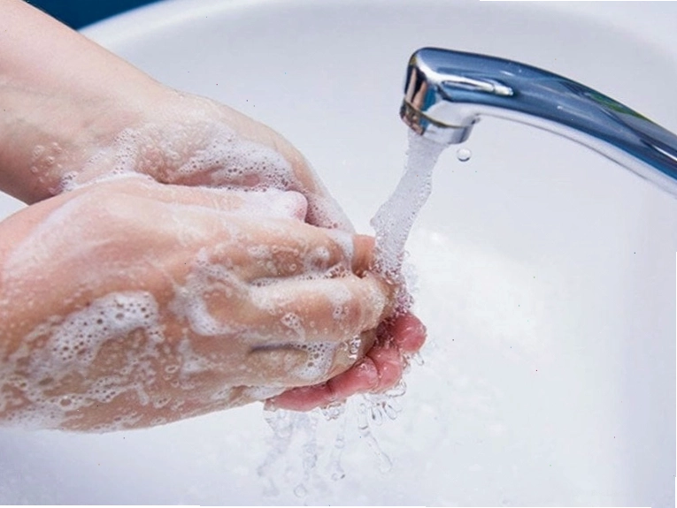 Người đang rửa tay bằng xà phòng dưới vòi nước