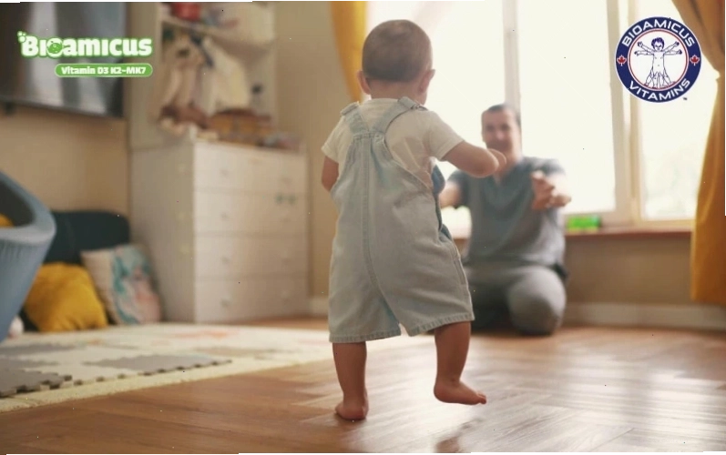Trẻ em đang thực hiện bài tập đi bộ với sự hỗ trợ của người lớn